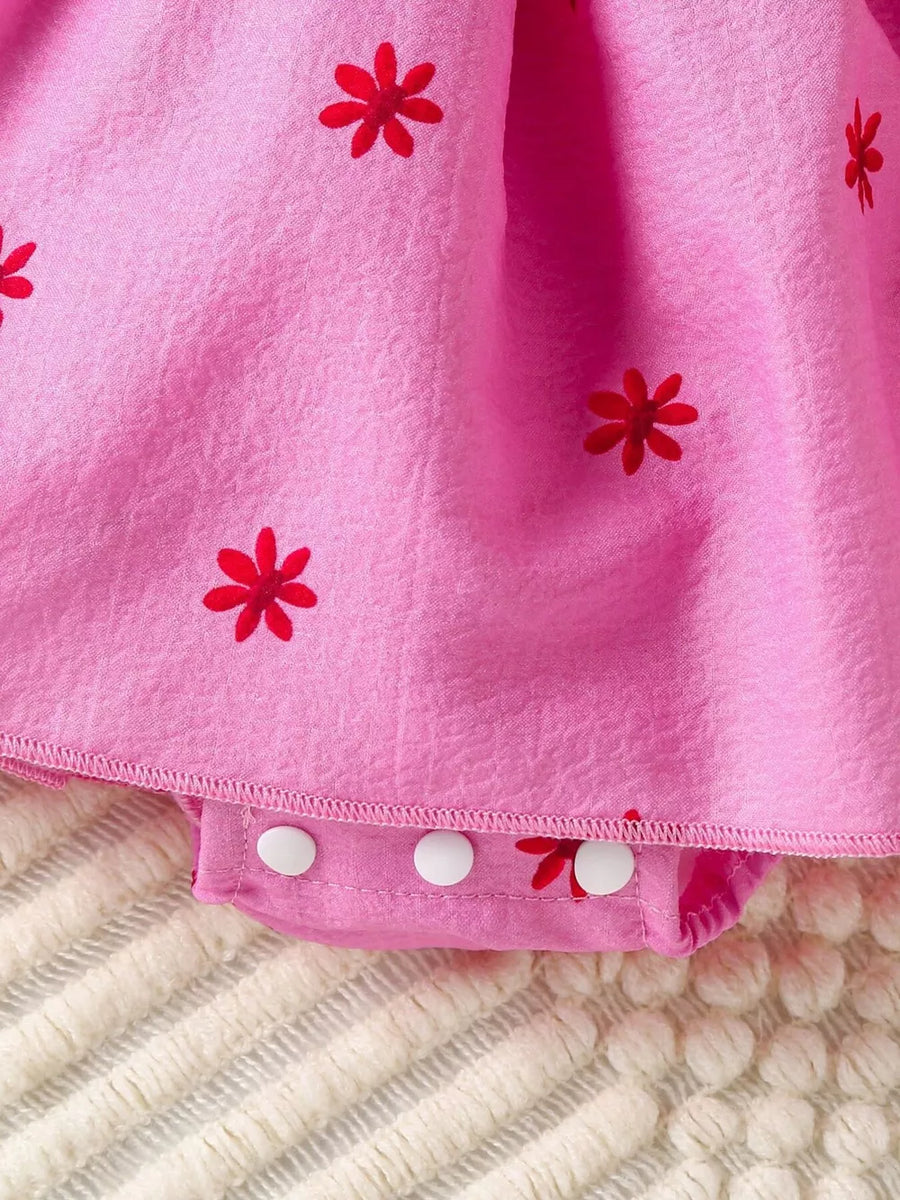 Pink cotton baby dress with red floral print and snap closure bodysuit.