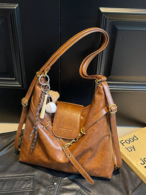 Convertible brown PU leather hobo bag with baseball and heart charms and adjustable strap.
