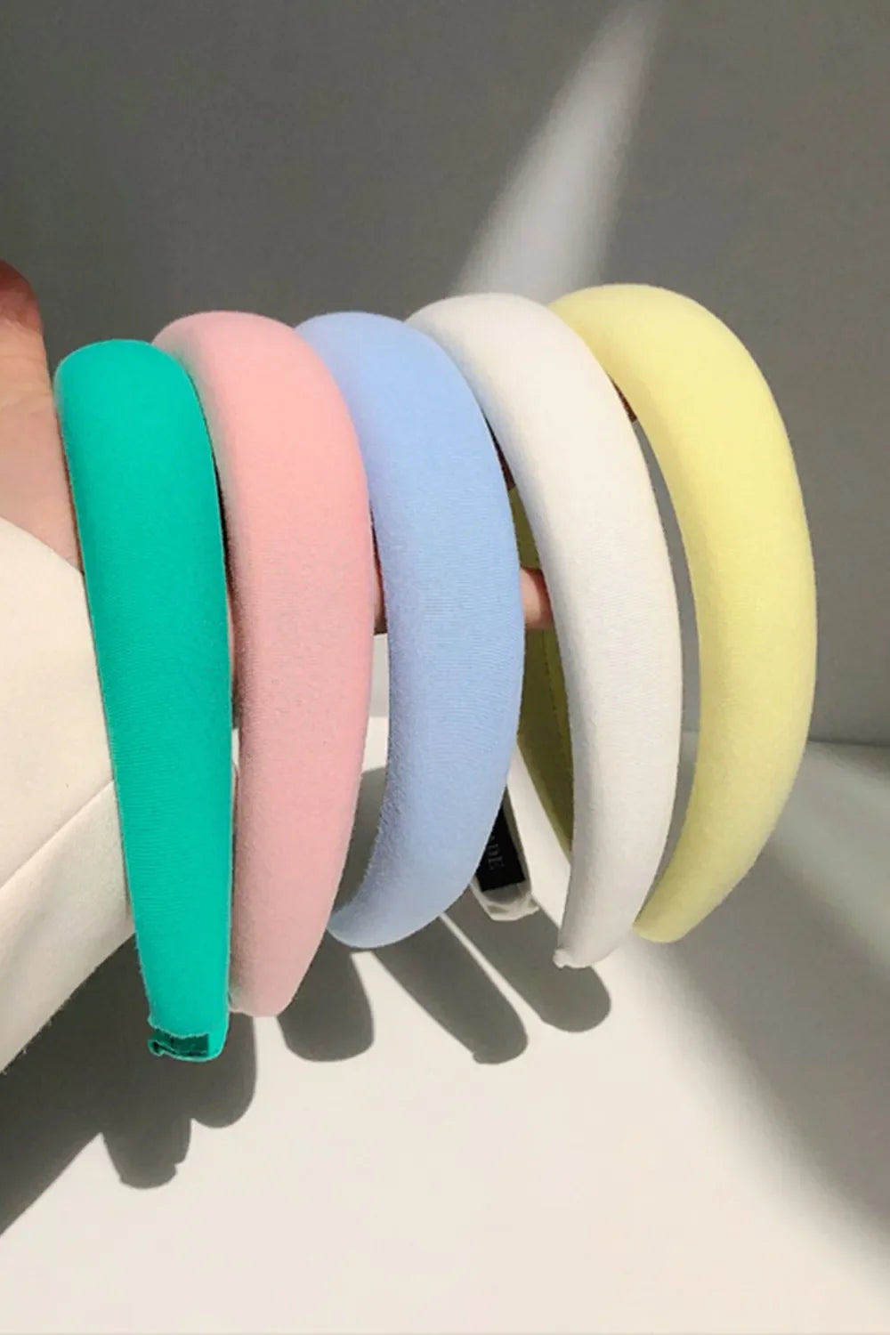 Padded headband with textured fabric in turquoise, pink, light blue, white, and light yellow.