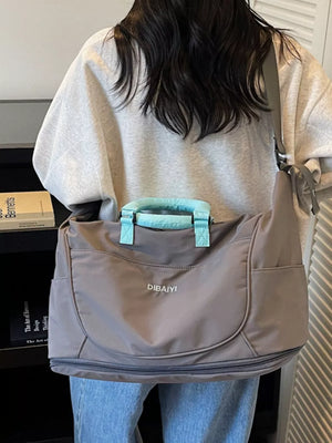 Gray Oxford cloth duffel bag with light blue handles and crossbody strap.
