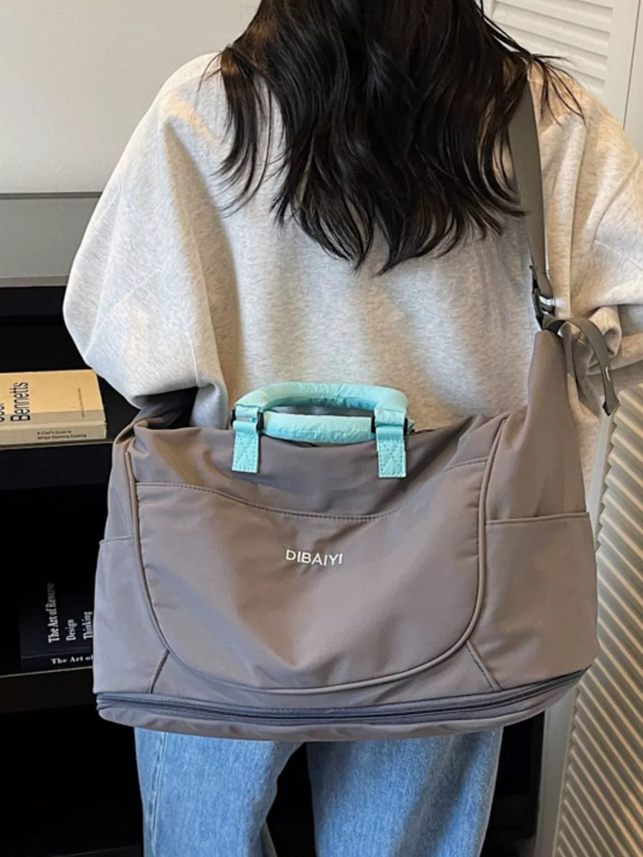 Gray Oxford cloth duffel bag with light blue handles and crossbody strap.