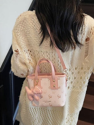 Charming mini crossbody bag in blush pink with a deer print and a cute dog charm.