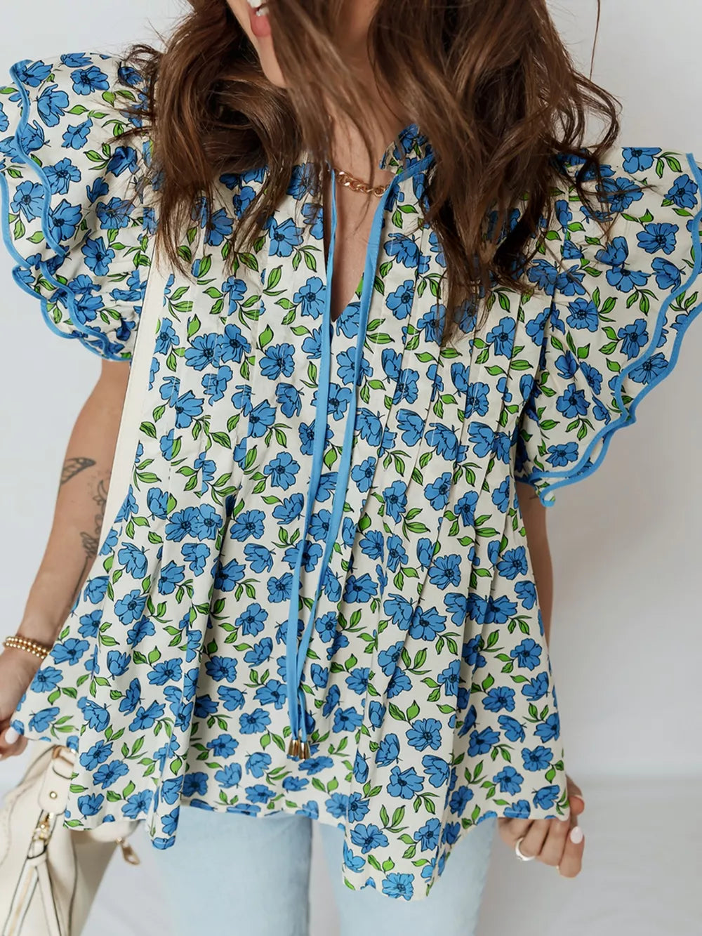 Floral ruffle sleeve tie-neck blouse with blue floral print and frill trim.