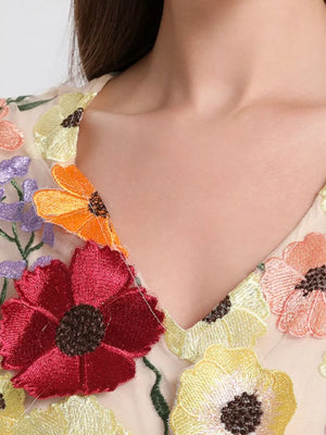 Sheer v-neck dress with colorful floral embroidery.