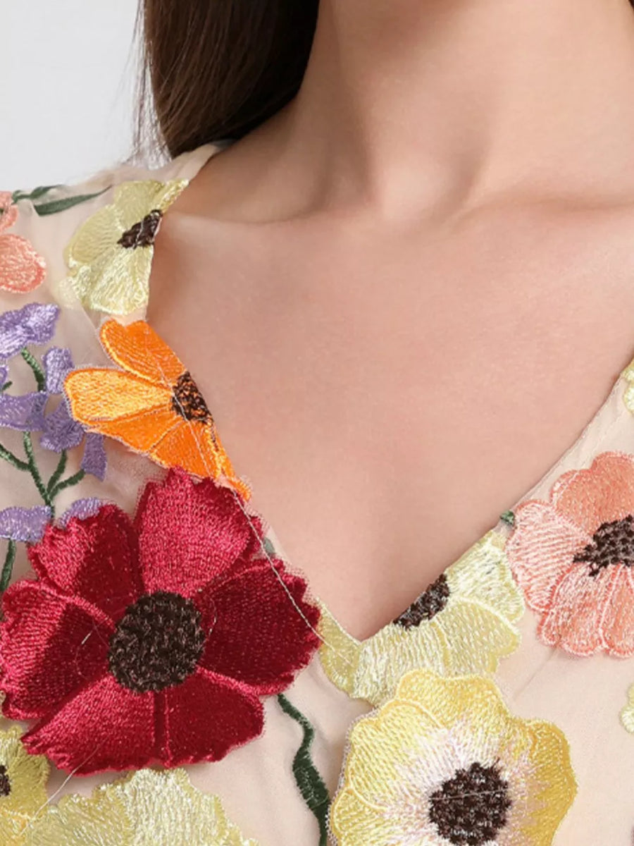 Sheer v-neck dress with colorful floral embroidery.