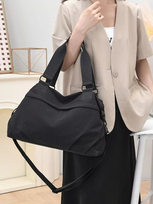 Black nylon duffel bag with adjustable strap and gold hardware details.