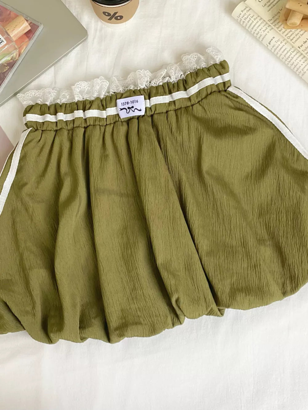 Army green mini skirt with lace trim, gathered waist, and white side stripes.