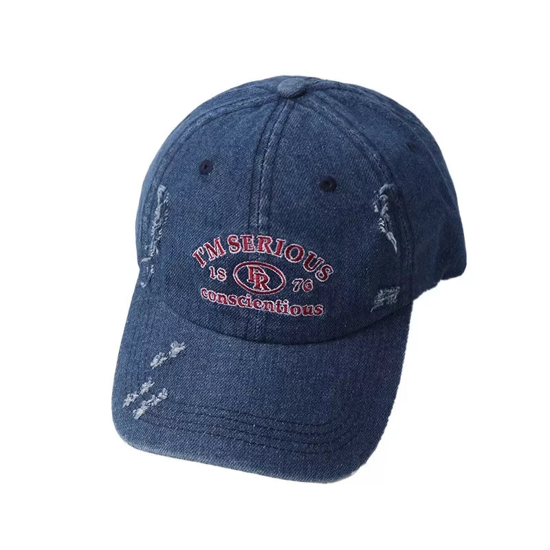 Denim baseball cap with distressed details and embroidered text.