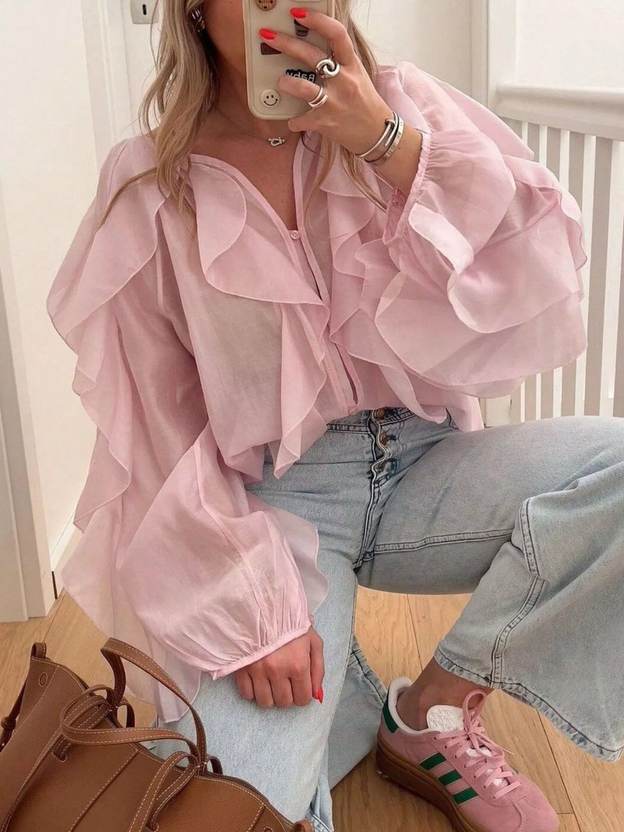 Pink sheer long-sleeve blouse with cascading ruffles and a V-neck.