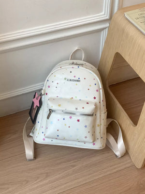 White mini backpack with colorful star print and front zip pocket.