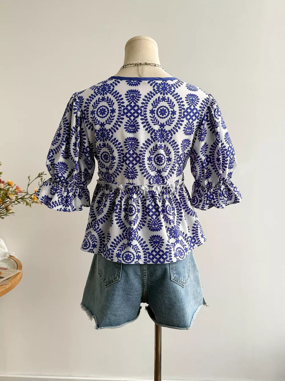 Chic floral blouse with 3/4 ruffled sleeves and tie-front detail, paired with denim shorts.