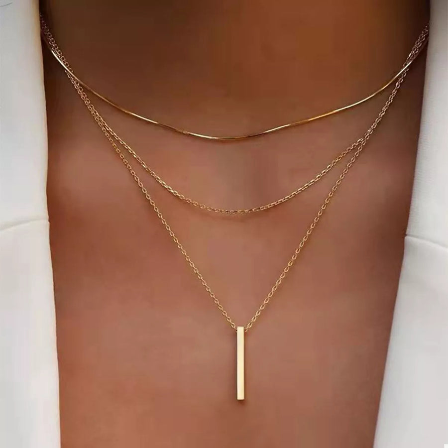 Gold layered bar pendant necklace with delicate chains.