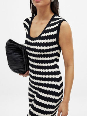 Sleeveless striped knit midi dress with scoop neck and side slit, held with a black clutch.