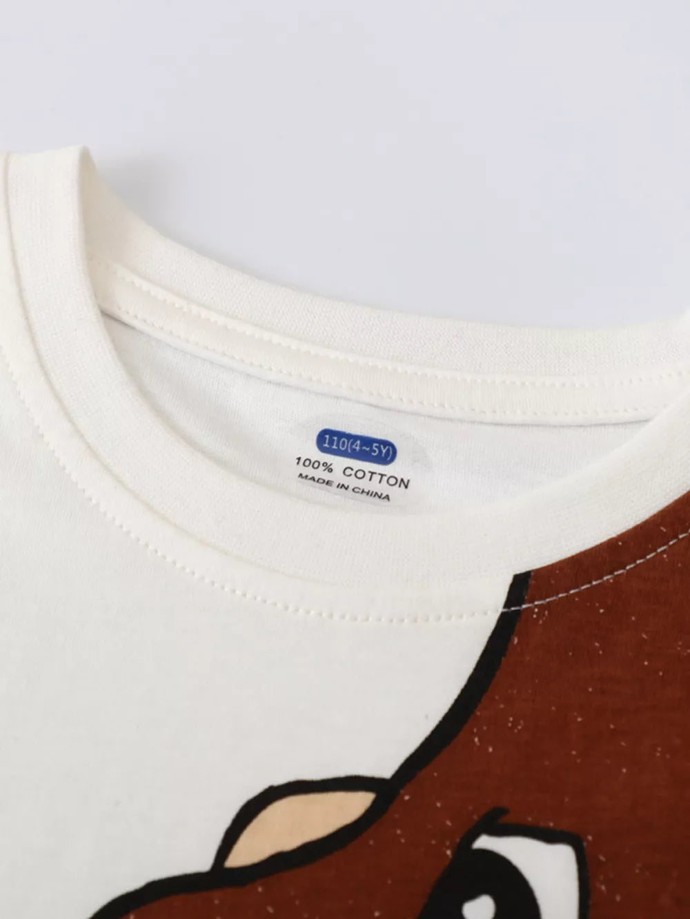 Toddler white cotton tee with dinosaur graphic detail and size tag.