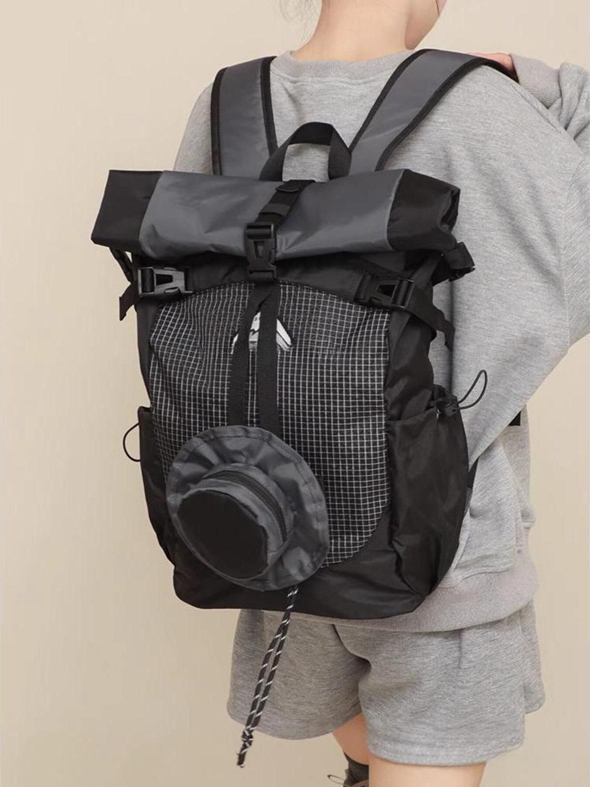 Sleek roll-top nylon backpack in black with gray accents and a checkered front panel.