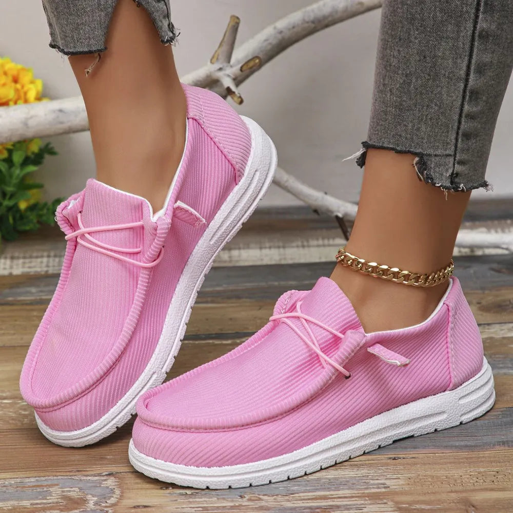 Pink textured slip-on espadrille sneakers with white soles and pink laces.