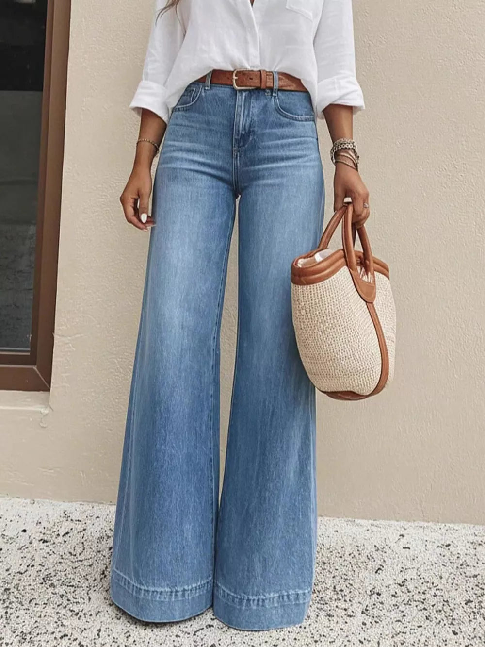 Light wash denim wide-leg jeans with pockets and a high waist, styled with a white shirt and brown belt.