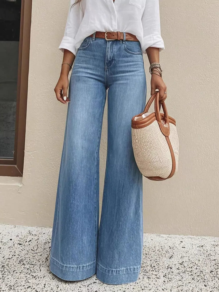 Light wash denim wide-leg jeans with pockets and a high waist, styled with a white shirt and brown belt.