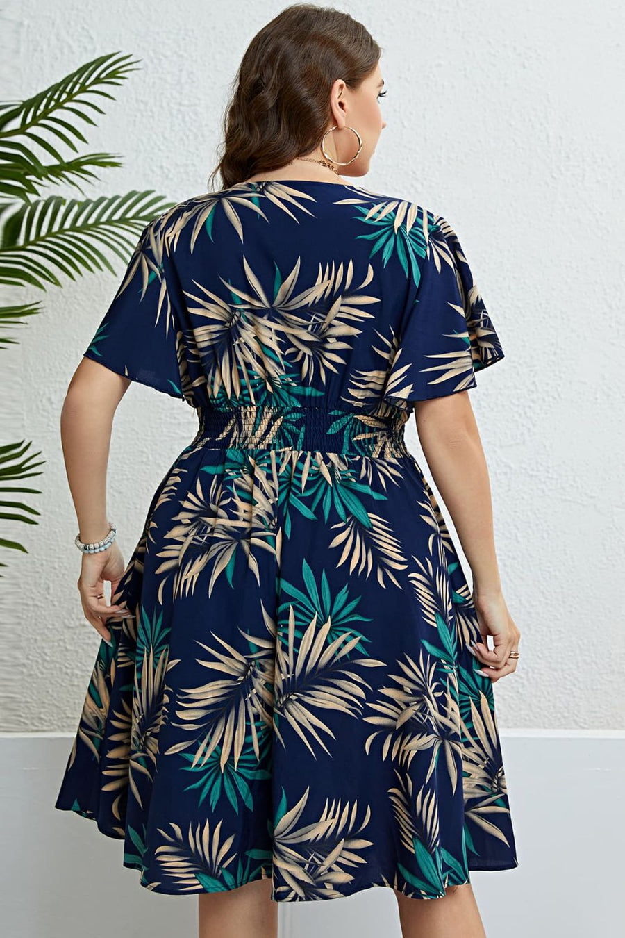 Dark navy midi dress with empire waist, flutter sleeves, and a tropical palm print.