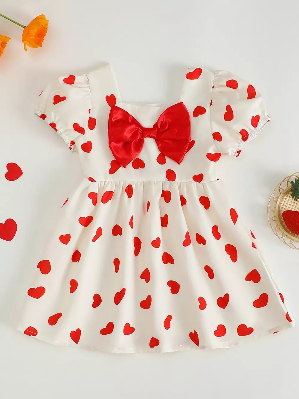 Baby dress with red hearts, puff sleeves, square neck, and red bow detail.