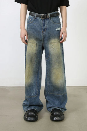 Faded patchwork denim palazzo trousers in medium wash with distressed details and wide legs.