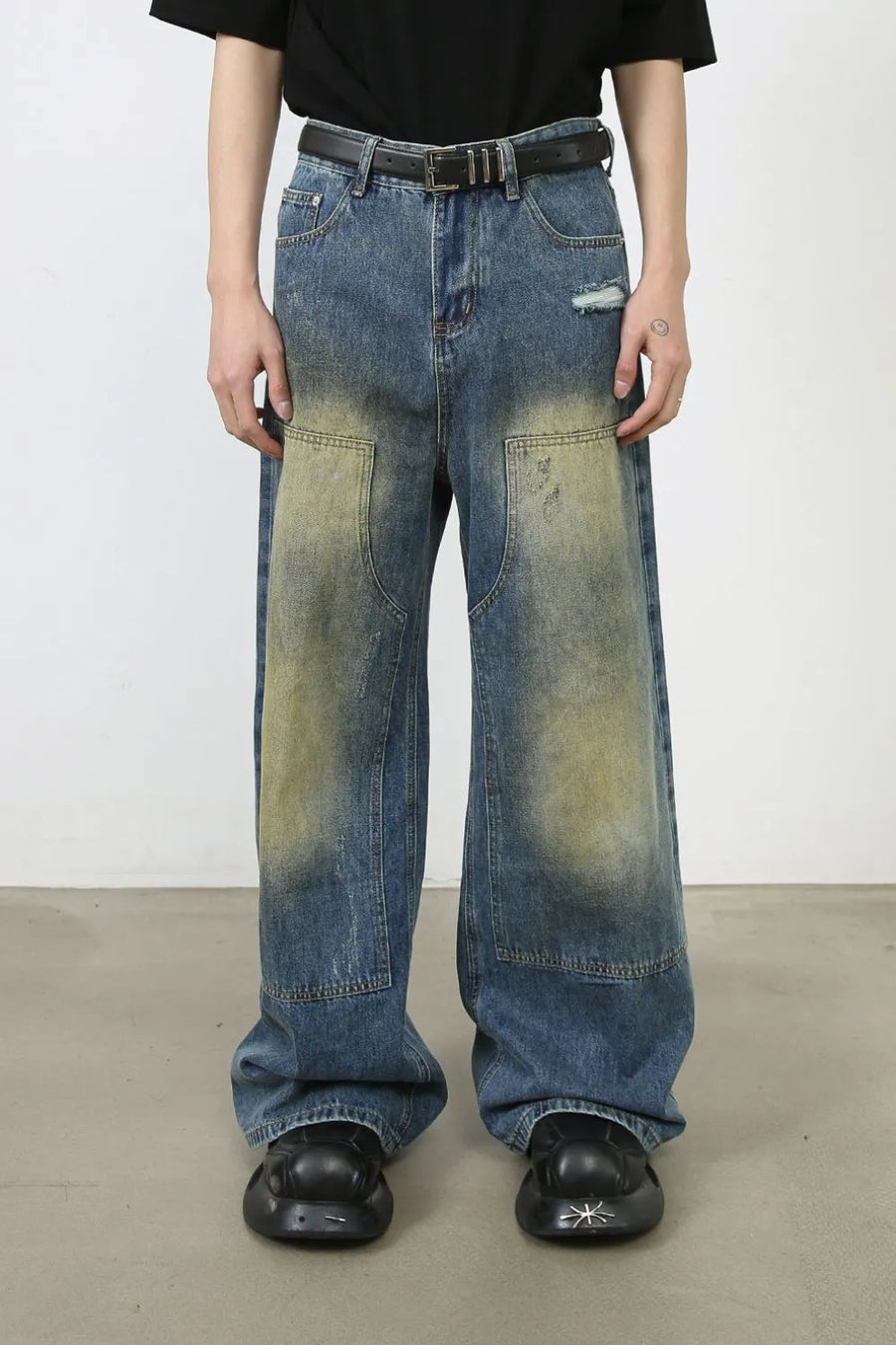 Faded patchwork denim palazzo trousers in medium wash with distressed details and wide legs.