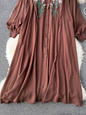 Brown cotton maxi dress with embroidered floral detail and tie neck.