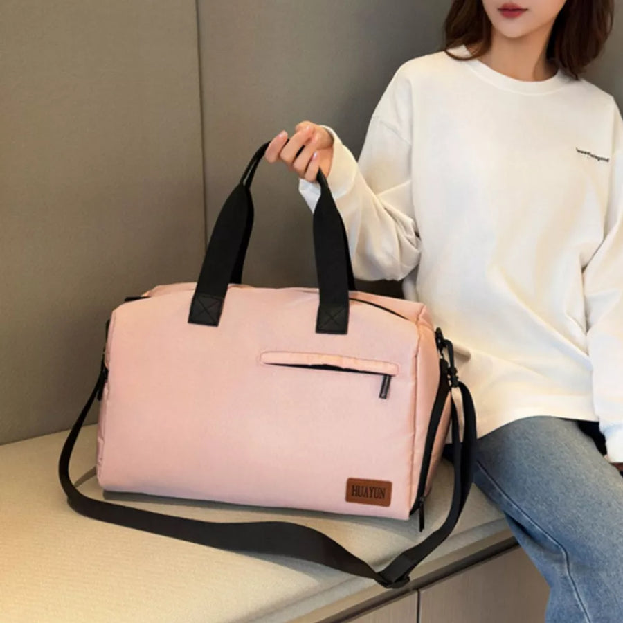 Pink nylon travel duffel bag with adjustable strap and zippered pocket.
