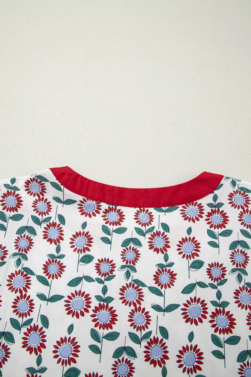 Vibrant floral tiered midi dress with red floral pattern and red neckline.