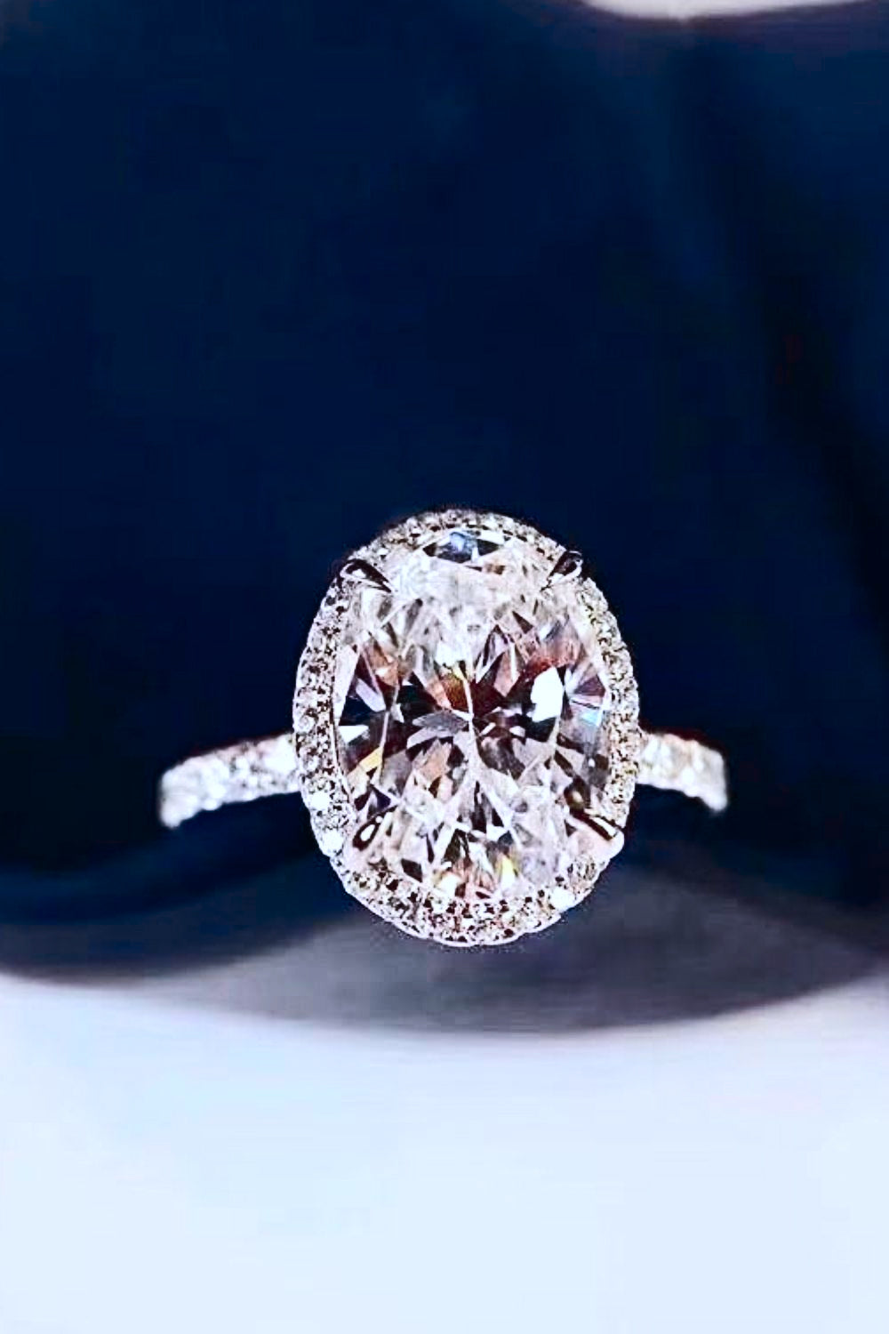 Halo oval diamond engagement ring with pave band in white gold.