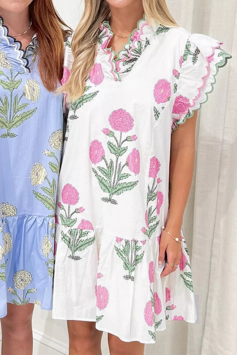 White floral ruffle mini dress with pink floral print and scalloped trim.