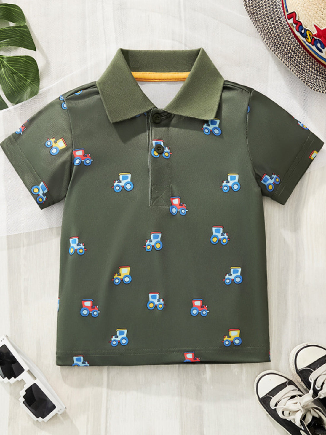 Children's green tractor print polo shirt with short sleeves and a collared neckline.