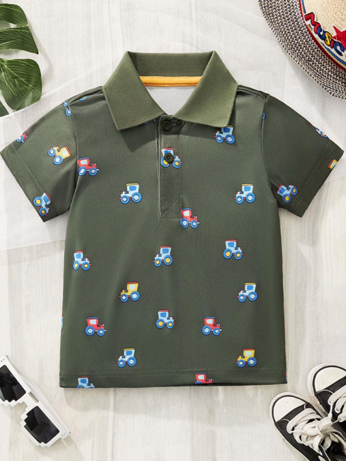 Children's green tractor print polo shirt with short sleeves and a collared neckline.