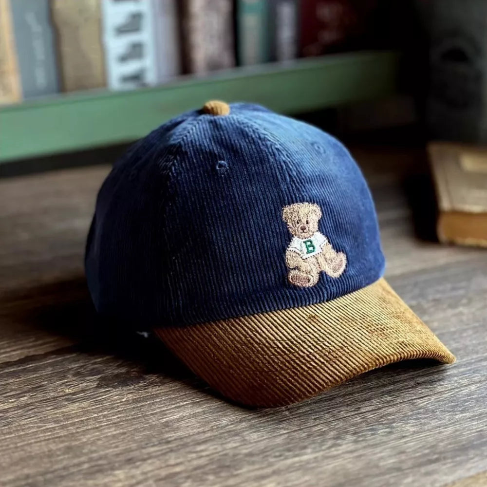 Navy corduroy baseball cap with tan brim and embroidered bear detail.
