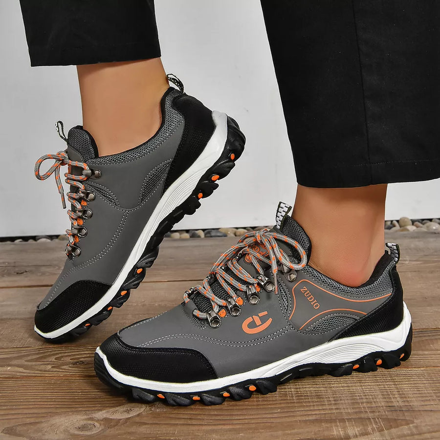 Grey lace-up low-top sneakers with patterned orange laces and black accents