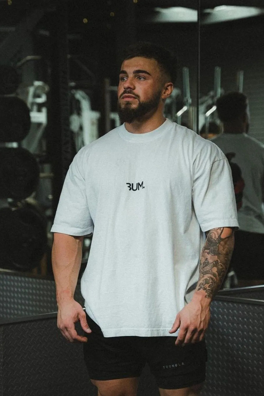 Oversized white graphic tee with black statement logo and short sleeves.