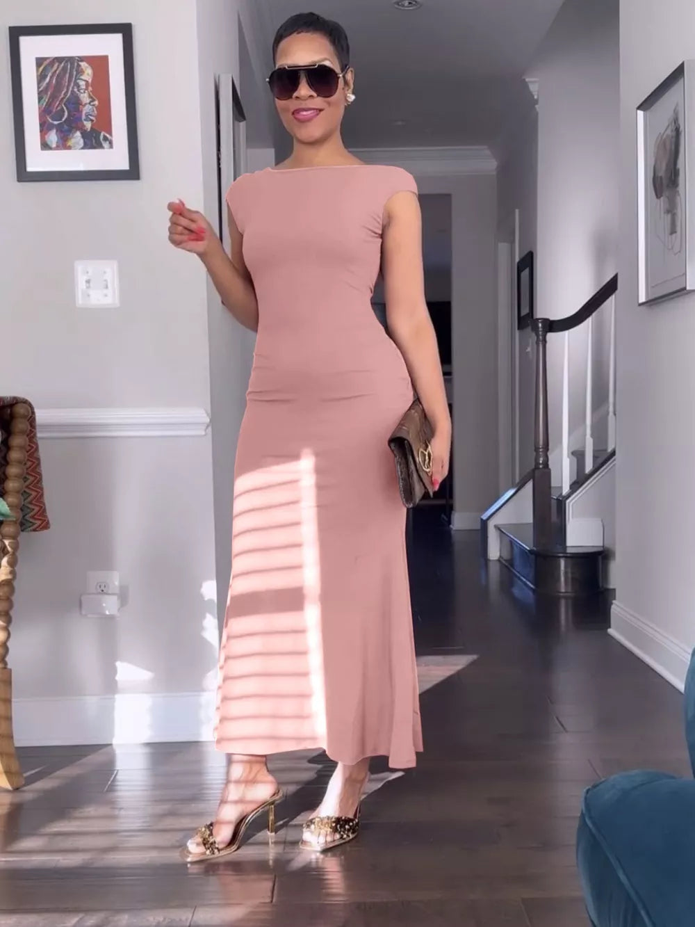 Sleek backless cap sleeve maxi gown in coral with boat neckline and body-skimming cut.