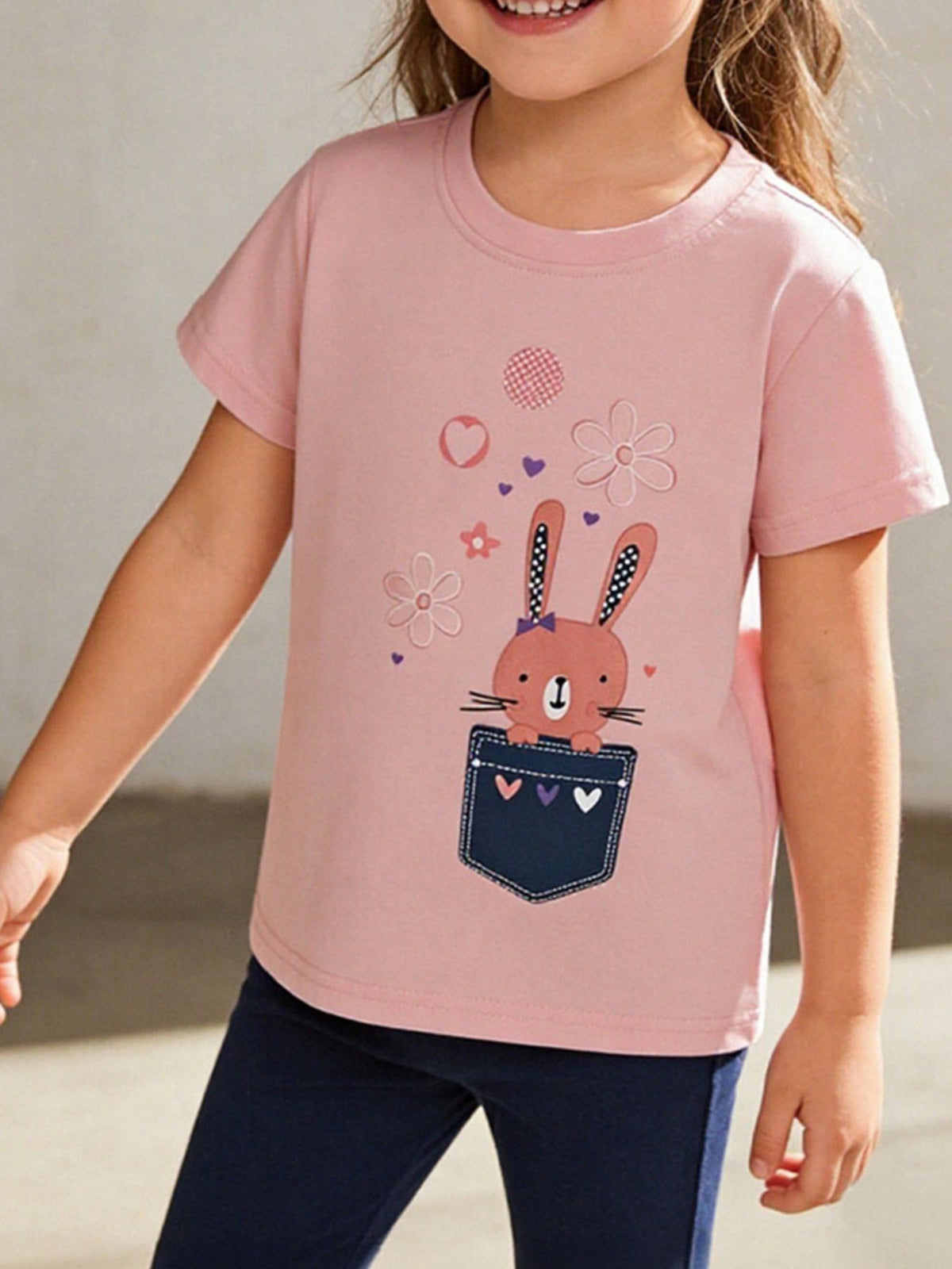 Pink toddler t-shirt with a cute bunny graphic peeking out of a denim pocket.