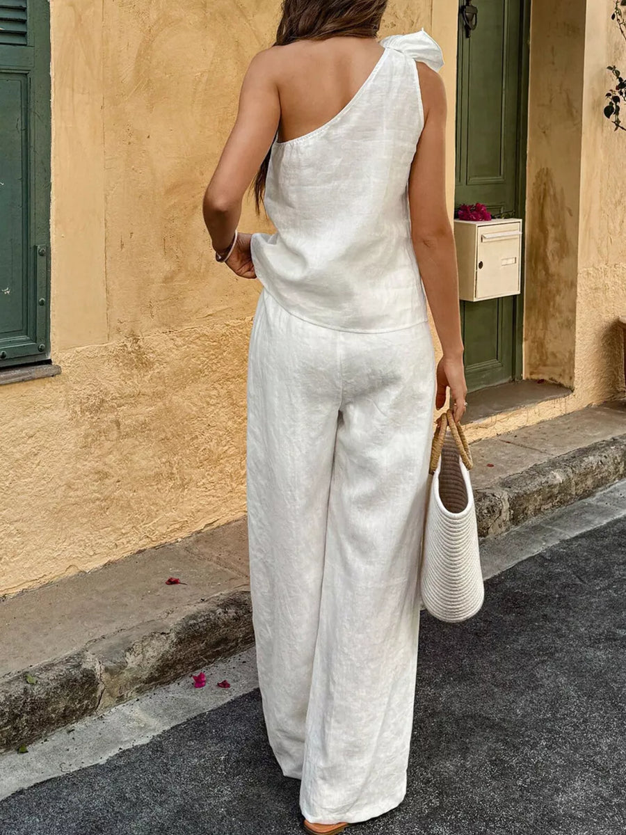 White cotton one-shoulder top with bow detail and wide-leg pants ensemble.