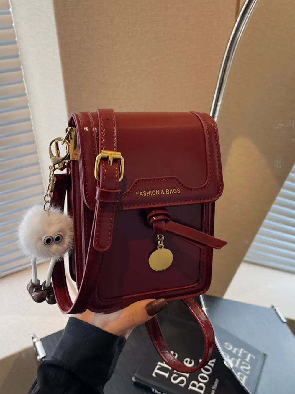 Deep Red mini crossbody bag in shiny pu leather with gold hardware and a fluffy charm.