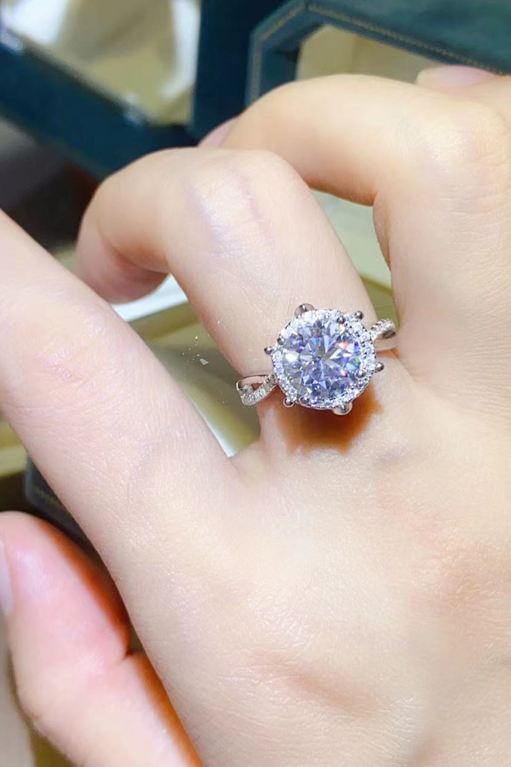 Silver moissanite engagement ring with a halo and twisted band.