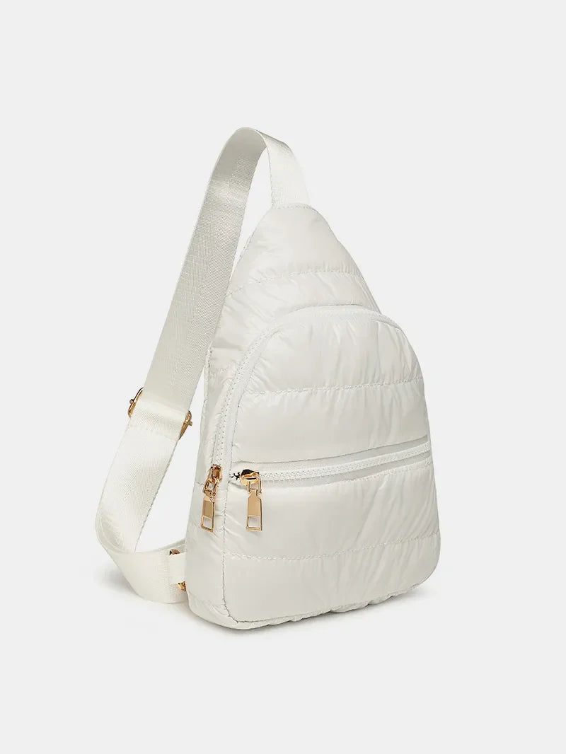 Glossy padded sling bag in white with gold zippers and adjustable strap.