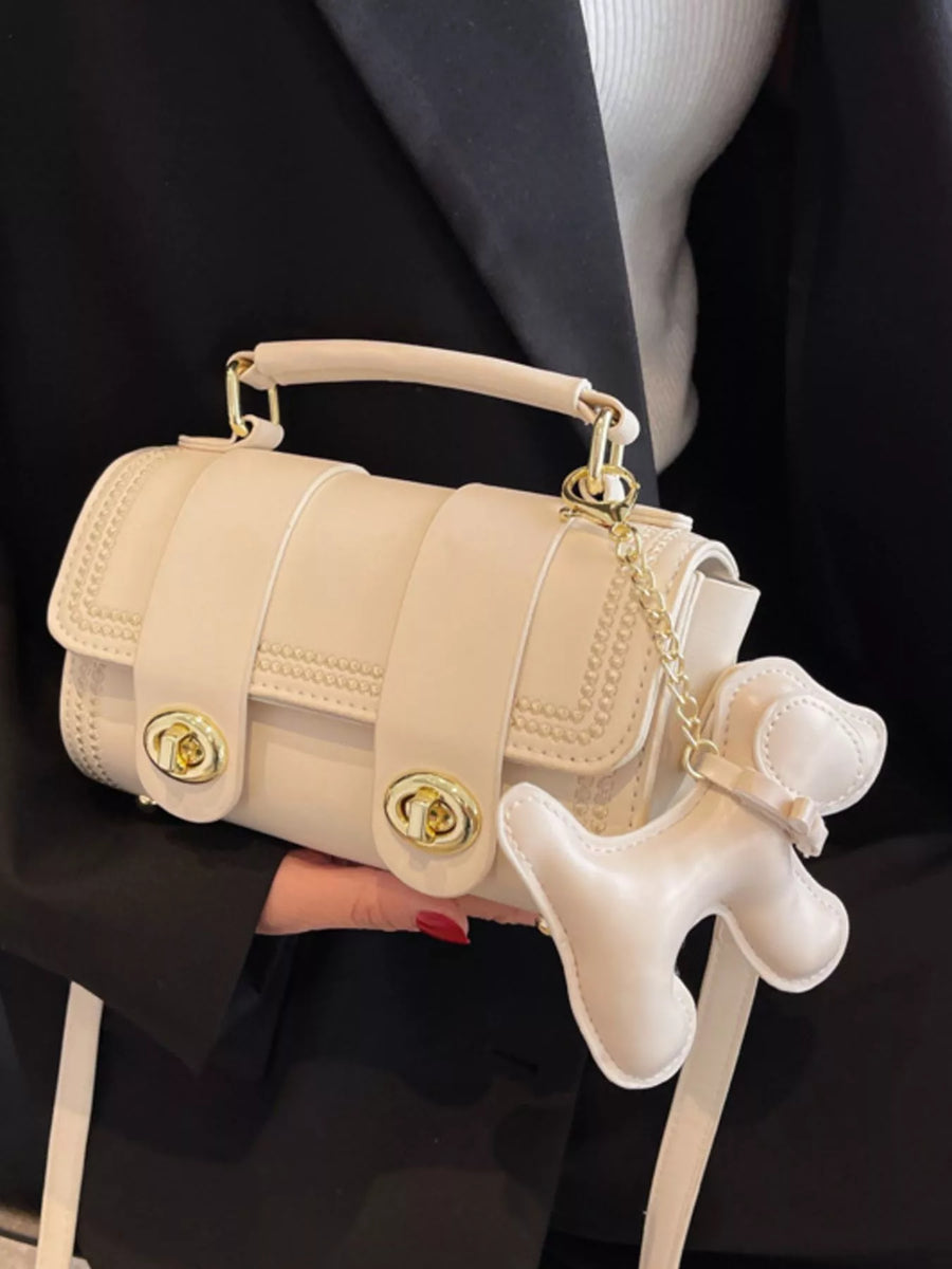 Mini beige PU leather crossbody bag with gold hardware and a dog charm accessory.