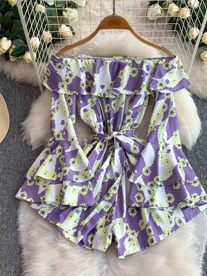 Playful off-shoulder ruffled romper in Color Strips with floral pattern and bow tie waist.