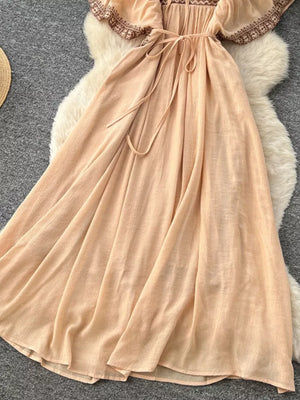 Peach V-neck maxi dress with embroidered details and a tie waist.
