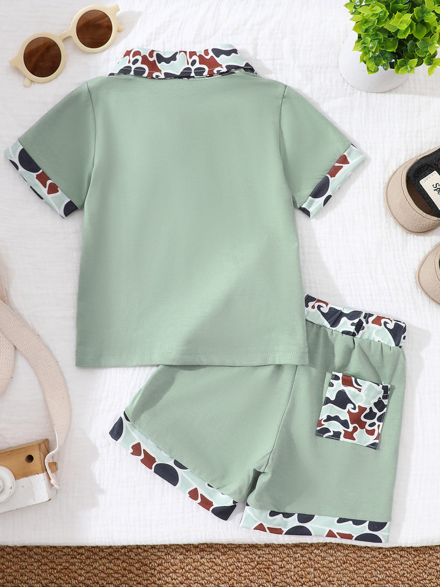 Sage green baby polo and shorts set with camouflage collar and trim.