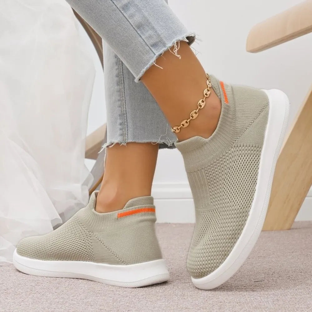 Airy knit slip-on sneakers in light grey with orange accent detail and white soles.