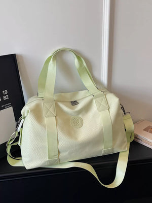 Chic perforated large duffle bag in light green with dual handles and adjustable strap.