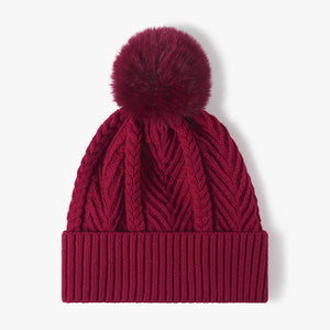 Burgundy chevron knit beanie with ribbed cuff and faux fur pom.