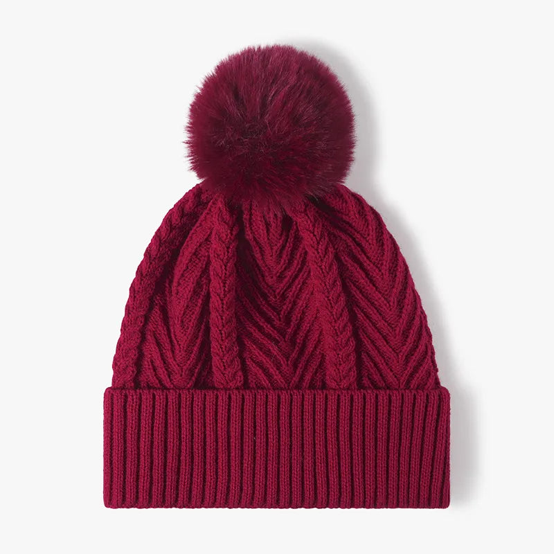 Burgundy chevron knit beanie with ribbed cuff and faux fur pom.